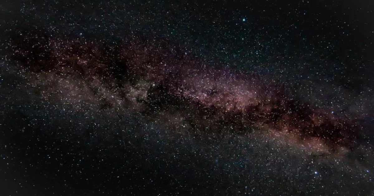 A clear, star-filled dark night sky stretching over a quiet horizon